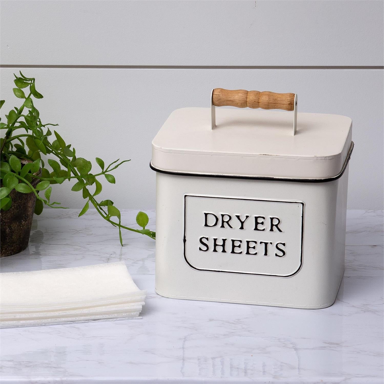 Add a touch of vintage style to your laundry room organization with this Dryer Sheets Storage Bin. Made of metal, it features an ivory white weathered finish with black lettering and trim and a vintage style wood handle. 7.25W x 6.25D x 8H