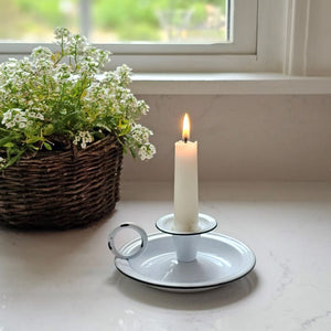 Add that centuries old farmhouse look to any bedside bureau or tabletop with our White Chamberstick Taper Candle Holder. It has the classic finger loop and tray, which made it easy to carry candles from room to room back in the day. The white enamel finish adds a sweet cottage feel. Taper candle not included.&nbsp; 5"W x 2½"H
