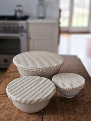 Our Fabric Bowl Covers offer a touch of nostalgia along with a heap of function, which is just what every modern farmhouse needs. This set of bowl covers, in three sizes, is perfect for making bread, covering a salad to be served later, cookies to bring to a neighbor. Made from a 100% cotton, they fit snugly over bowls. The fabrics have a classic vintage farmhouse feel. The set has three different covers with tan and oatmeal gingham and ticking stripes.