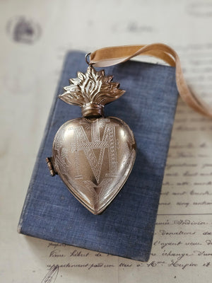 Introducing the Sacred Heart Locket Box, the perfect blend of vintage style and old-world charm. Crafted from aged metal with a golden bronze finish and intricate etchings, this locket box offers a timeless storage solution for your sacred treasures. Hang it from a chain or ribbon with the attached loop (Ribbon not included).
