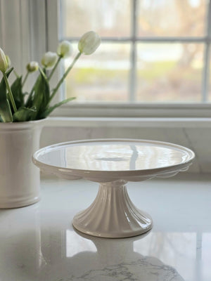 The Scalloped Edge Creamware Cake Stand is perfect for displaying your creative creations. Great for cheese, cookies, cakes and more, this vintage style bakery shop pedestal makes an ideal addition to any creamware collection. The sweet ruffled edge design gives this cake stand added charm. Antique White. 10.75" Diam x 4.75"H