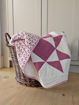 Make this Sweet Sawtooth Star Quilted Throw a treasured heirloom. A fresh take on the iconic sawtooth star quilt block, this organic cotton patchwork throw is hand quilted by skilled artisans. The antique-inspired design features pinkish-lilac and magenta stars with a playful pin dot pattern. Fully reversible, the quilt backing showcases a coordinating floral print.