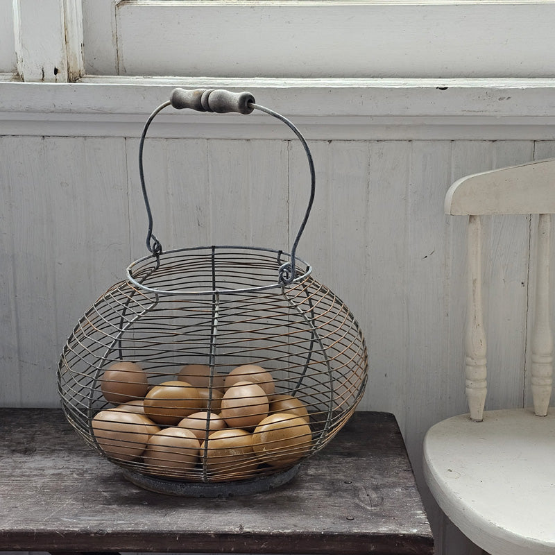 This Vintage Style Wire Egg Basket is the perfect addition to your farmhouse style decor. There are so many uses for this country classic. Collect eggs from the chicken coop or gather veggies from the garden. Featuring an aged patina, this rusted metal wire basket, with weathered wooden handle, looks as if it was found in an old barn. The thin wire frame is perfectly imperfect, giving it antique charm.