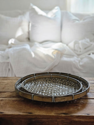 This Weathered Bamboo Tray Set lends an organic touch, infused with a rustic nature. The aged muted grey finish gives them a timeless, antique feel and the woven texture adds a unique touch. Use them as a tabletop accent for a touch of sophistication or hang them on the wall for a rustic look. Set of two. LG. 14.25 Diam x 2"H, SM 11.75" Diam x 1.50"H