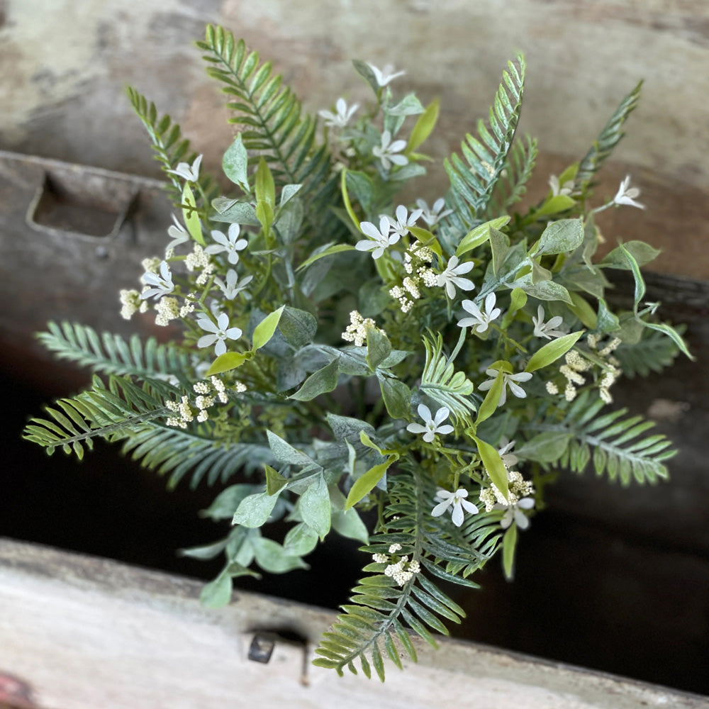 Add a sweet touch to any vase, basket or pot with our White Blossoms Fairy Fern Bush. This faux stem features a beautiful melody of airy ferns, lightly powdered mixed greenery, petite blooms, and tiny bubble berry shoots. Makes an easy go-to accent for fans of white farmhouse style decor. 12"H. 