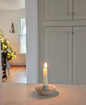 This simple White Glazed Ceramic Taper Candle Bowl, with its quiet elegance and clean design, adds instant ambience to any room. This ceramic taper holder is equal parts modern simplicity and organic imperfection. Features a white glaze finish with a natural, un-glazed bisque exterior.  Fits regular size tapers (candle not included). 4.25" diam x 1.25"H