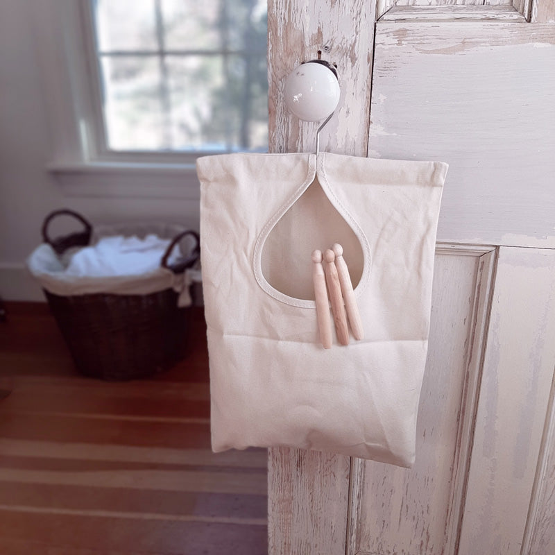 Bring a little vintage flare to your laundry day. There's nothing better than fresh, crisp laundry off the line. Keep this sturdy natural colored canvas Vintage Style Clothes Pin Bag near at hand and never have to fumble for a clothes pin again. Features a durable, washable, water-repellent canvas bag that can hold up to 100 clothespins, a swivel hook for effortless hanging, and reinforced stitching around the opening for extra durability. 11"W x 15"H