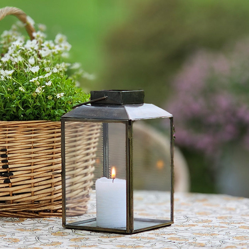 The Aged Iron Lantern adds rustic ambiance to any occasion.&nbsp; Features an antique bronze style finish and glass windows to protect the flame. Includes a door on one side and a wire handle for hanging. Makes a beautiful tabletop presentation. Holds one pillar candle. Each sold separately. Includes one lantern. 