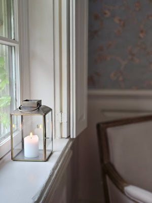 The Aged Iron Lantern adds rustic ambiance to any occasion.&nbsp; Features an antique bronze style finish and glass windows to protect the flame. Includes a door on one side and a wire handle for hanging. Makes a beautiful tabletop presentation. Holds one pillar candle. Each sold separately.