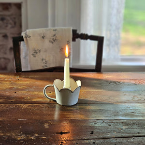 Our Antique White Scalloped Taper Candle Cup features an aged ivory finish with hints a grey metal peaking through. The sweet  scalloped edging lends a country cottage style. The cup has plenty of space between the holder and the sides, making it the perfect choice for displaying a candle ring! This taper candle holder features a handle for old-timey chamberstick charm. This cup is ideal for catching dripping wax. Measures 3.75" in diameter, 5" wide with handle, 3"H and holds a standard taper.