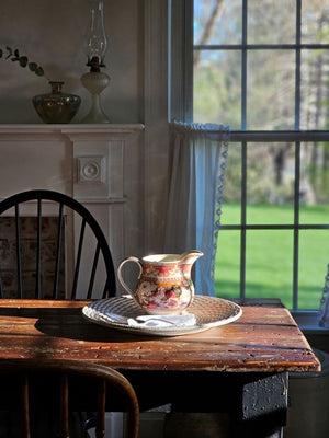 The Antique Style Old World Floral Pitcher brings a touch of elegance and vintage romance to any occasion. This porcelain pitcher features a richly detailed floral design, highlighted by a warm, cream-toned glaze that gives the piece a soft, antique-inspired appearance. The base color is not a bright white, but rather a subtle ivory/cream tone that enhances the depth and character of the intricate floral artwork and ornate border detailing.