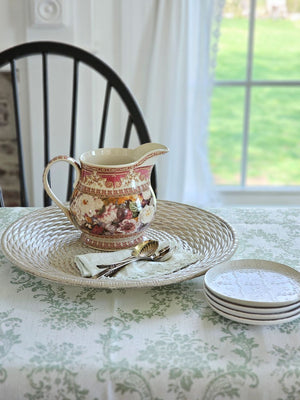 The Antique Style Old World Floral Pitcher brings a touch of elegance and vintage romance to any occasion. This porcelain pitcher features a richly detailed floral design, highlighted by a warm, cream-toned glaze that gives the piece a soft, antique-inspired appearance. The base color is not a bright white, but rather a subtle ivory/cream tone that enhances the depth and character of the intricate floral artwork and ornate border detailing.