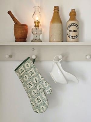 Bring timeless cottage elegance to your kitchen with the Artichoke Oven Mitt. Showcasing a vintage-inspired green artichoke motif against an ivory backdrop, it is accented with contrasting piping and a convenient corner loop for easy hanging. This quilted mitt offers reliable heat protection while enhancing your kitchen decor with refined charm. 100% cotton with polyester batting.
