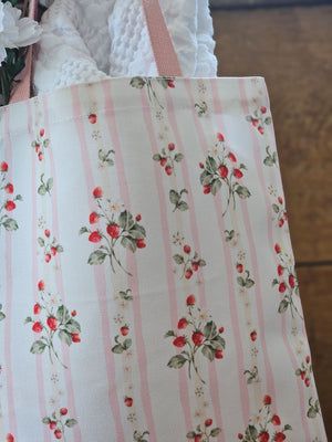 The Bespoke Strawberries and Stripes Tote Bag is perfect for groceries, shopping excursions at the farmers market or a day at the beach. This cotton canvas tote features a vintage-inspired strawberry design with sweet pink stripes and a pink handle. Made in England, the bespoke design is created with a love of color, heritage and intricate design while celebrating craftsmanship, storytelling and a strong sense of seasonality.