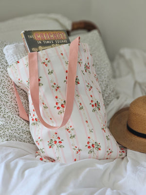 The Bespoke Strawberries and Stripes Tote Bag is perfect for groceries, shopping excursions at the farmers market or a day at the beach. This cotton canvas tote features a vintage-inspired strawberry design with sweet pink stripes and a pink handle. Made in England, the bespoke design is created with a love of color, heritage and intricate design while celebrating craftsmanship, storytelling and a strong sense of seasonality.
