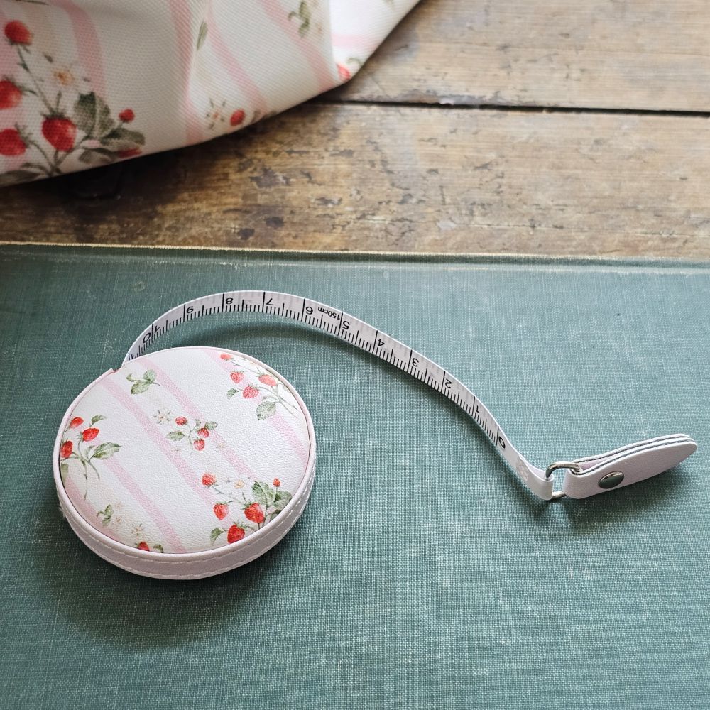 The Bespoke Strawberries and Stripes Travel Tape Measure is a handy little tool to keep on your desk or stash away in your purse for trips to the flea market. This faux leather compact tape measure features a vintage-inspired strawberry design with sweet pink stripes.