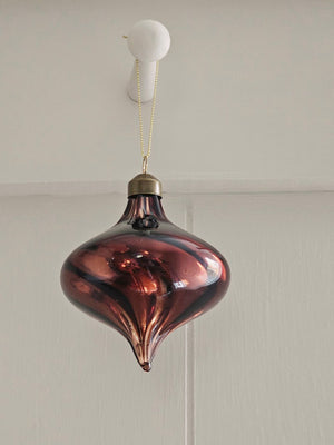 Add ambiance to your holiday display with this exquisite Bronze Glass Teardrop Ornament crafted from warm red-brown glass that catches the light with understated elegance. The subtle swirl pattern adds visual depth, while the antiqued brass cap provide a refined finishing touch.