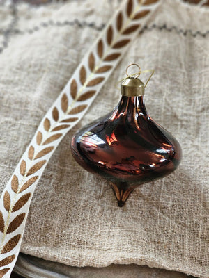Add ambiance to your holiday display with this exquisite Bronze Glass Teardrop Ornament crafted from warm red-brown glass that catches the light with understated elegance. The subtle swirl pattern adds visual depth, while the antiqued brass cap provide a refined finishing touch.