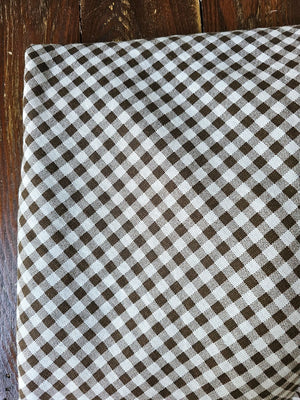 Enhance any occasion with the Brown and White Gingham Check Tablecloth with Ruffled Edge, where timeless country charm meets refined design. This durable and easy-care tablecloth sets the scene for countryside gatherings. The classic gingham pattern combined with the ruffled edge creates a sweet, vintage look no matter the season. Cotton/polyester blend. Available in two sizes: 72" Round and 56" x 120" Rectangle
