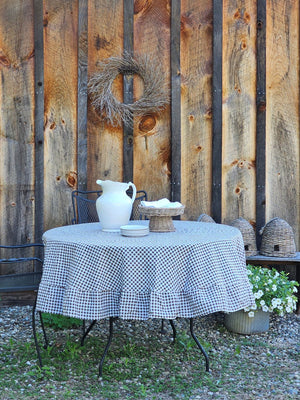 Enhance any occasion with the Brown and White Gingham Check Tablecloth with Ruffled Edge, where timeless country charm meets refined design. This durable and easy-care tablecloth sets the scene for countryside gatherings. The classic gingham pattern combined with the ruffled edge creates a sweet, vintage look no matter the season. Cotton/polyester blend. Available in two sizes: 72" Round and 56" x 120" Rectangle