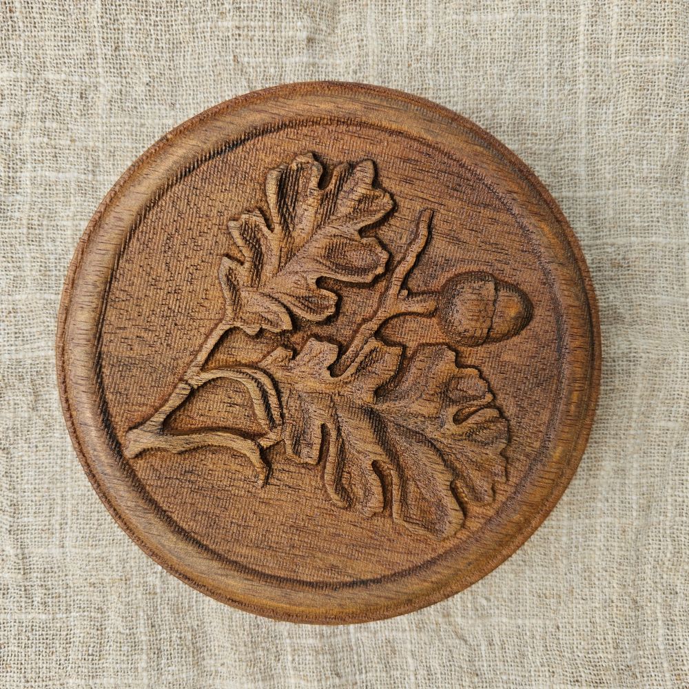 Our Carved Wood Acorn Wall Plaque lends down-to-earth rustic charm to any room. With its rich patina, this plaque will add a layer of texture and interest to your walls. It's an ideal choice for those seeking unique accents to bring warmth and beauty to their spaces. Crafted with dedication and passion, it's more than just decor - it's a testament to quality and craftsmanship. 5.75" Diam