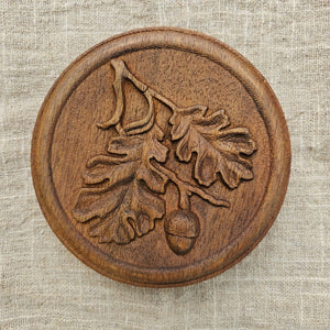 Our Carved Wood Acorn Wall Plaque lends down-to-earth rustic charm to any room. With its rich patina, this plaque will add a layer of texture and interest to your walls. It's an ideal choice for those seeking unique accents to bring warmth and beauty to their spaces. Crafted with dedication and passion, it's more than just decor - it's a testament to quality and craftsmanship. 5.75" Diam