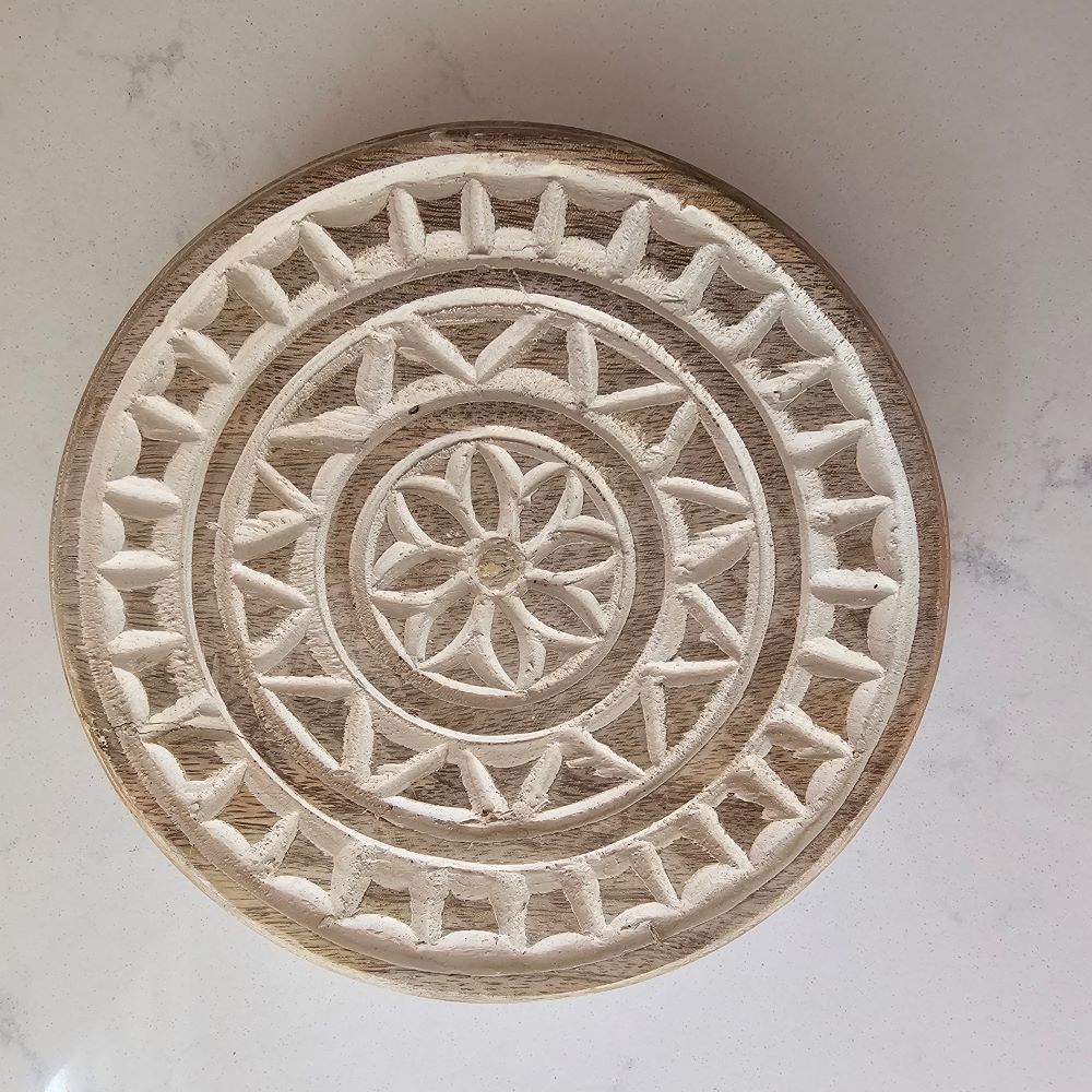This Round Carved Wood Riser makes a beautiful accent piece for any home. With its whitewash finish and carved design, it's both stylish and functional. An updated take on vintage bread boards, this footed riser can be used both decoratively, as a trivet and for displaying items. 7" diam x 1.25"H