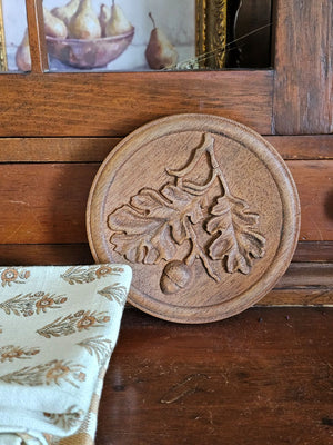 Our Carved Wood Acorn Wall Plaque lends down-to-earth rustic charm to any room. With its rich patina, this plaque will add a layer of texture and interest to your walls. It's an ideal choice for those seeking unique accents to bring warmth and beauty to their spaces. Crafted with dedication and passion, it's more than just decor - it's a testament to quality and craftsmanship. 5.75" Diam