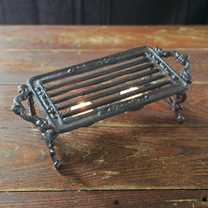 The Cast Iron Pot Warmer Trivet is perfect for adding an old-time touch with tons of practicality. This rectangular cast iron trivet is designed to keep teapots and food dishes warm. It features two tea light candle holders under the grill and an antique brown finish.