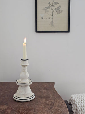 Add unique ambiance with the Chalky White Terracotta Taper Candlestick. Crafted from natural terracotta, this piece showcases an earthy texture beneath its soft chalky white finish, while delicate hand-painted black details add artisanal character. The beautifully imperfect design brings warmth and authenticity to any room, making it an ideal accent for farmhouse and country-inspired interiors seeking understated sophistication. 6" Diam x 10.5"H