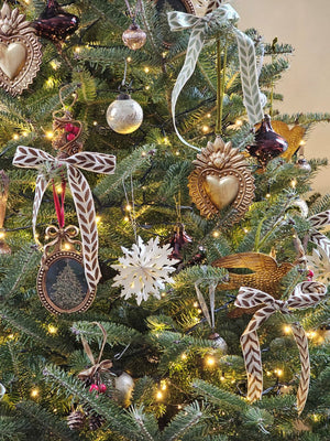 Our Sacred Heart Aged Gold Tin Ornament, with its distressed golden finish, evokes a sense of history, making it the perfect addition to any vintage-inspired decor. Handcrafted from aged metal with a rich, intricate design, this ornament exudes sophistication and old-world charm. Completed with a soft velvet ribbon for hanging, it is a must-have for any collector seeking exclusive and elegant treasures. 4.5" x 6"