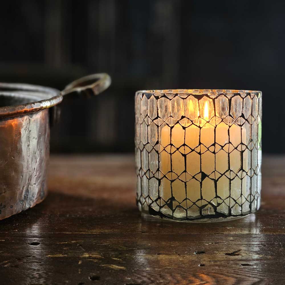 Add a bit of magical ambiance with our Clear Glass Mosaic Candle Holder. Features crystal clear glass that is hand cut and laid into intricate patterns and offset by a dark black grout in this updated take on mosaic. The glow of candlelight through the cut pattern is dreamy.