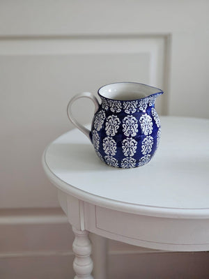 The Cordelia Blue Pitcher evokes the feeling of vintage finds from the European countryside. This ceramic pitcher features a sapphire blue glaze that is etched with a floral design, revealing the cool white under-layer. The etching gives it an embossed, textured feel. This sweet pitcher will make you feel transported to a farmhouse cottage in Provence. Available in two different floral patterns: small floral and block print style. Food safe.