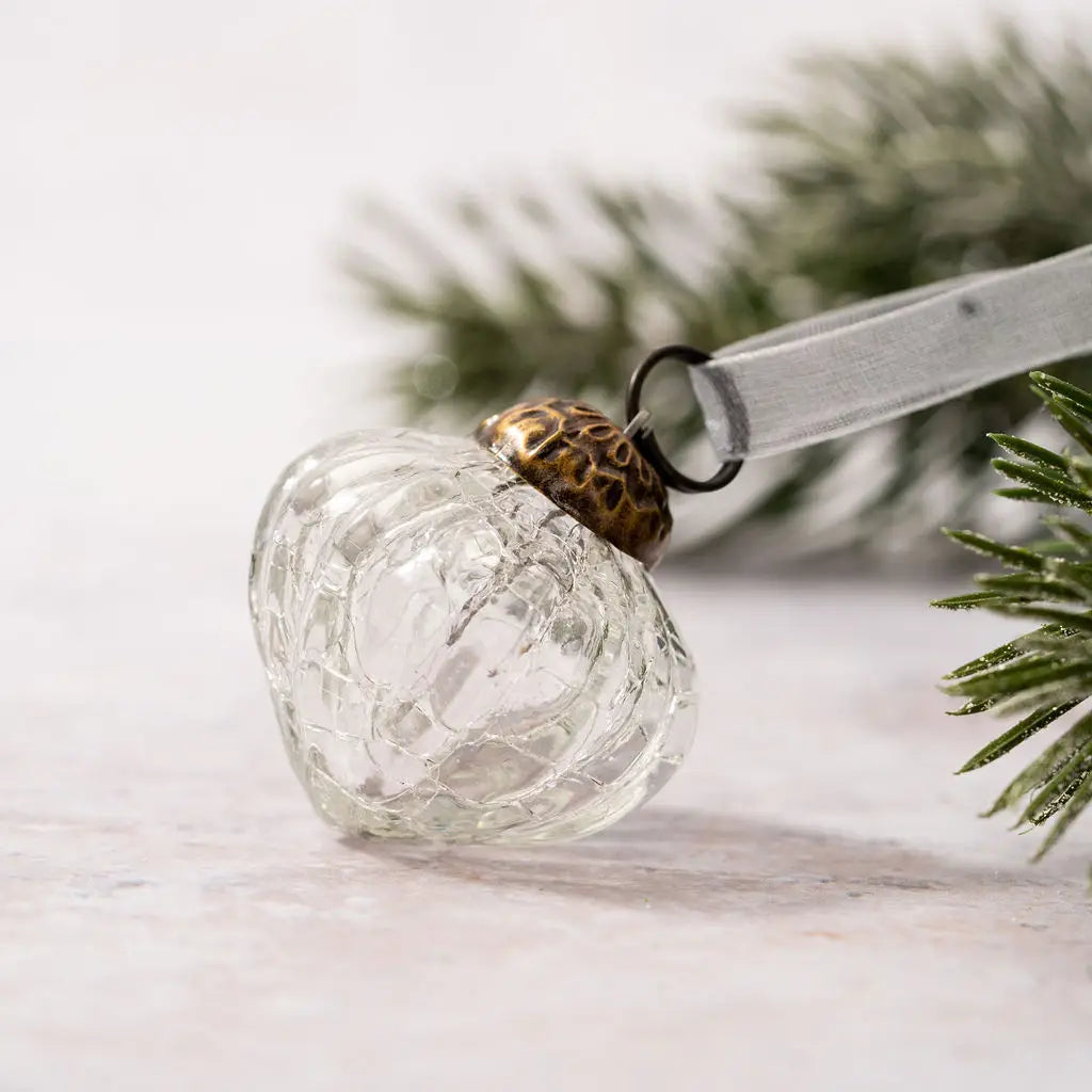 Our Vintage Crackle Glass Bulb Ornaments come as a set of six. These small hand-blown glass ornaments are inspired by vintage mercury glass bulbs. The glass bauble has a crackle glaze that is applied to the exterior when initially blown. This gives the glass an aged, crackled look. Each bulb is topped with an ornately detailed bronzed colored cap and finished with an organza ribbon for hanging. Each set contains six of the same design and color.