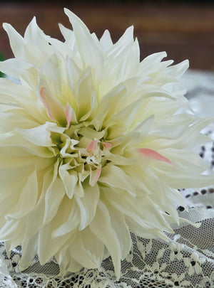 The Cream Dahlia Stem makes a stunning presentation. This faux floral is bursting with . realistic fabric petals with a soft hint of pink and rich green leaves. This Cream Dahlia stem is perfect for creating a farm table centerpiece that with wow-factor. Includes one stem to bring a touch of nature into your living space. 24"H