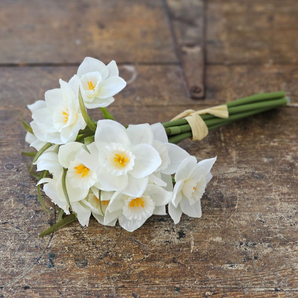 Bring understated elegance to your home with this refined collection of creamy white daffodils. Each bundle includes nine stems showcasing delicate narcissus blooms with soft yellow centers, complemented by natural greenery and budding accents. These faux flowers offer the timeless charm of spring blossoms without the maintenance, making them an enduring choice for any interior setting. 8.25"H
