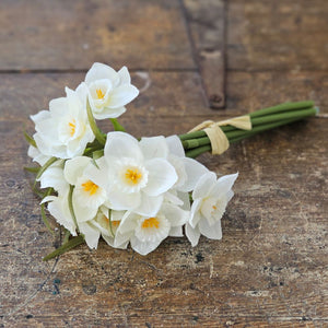 Bring understated elegance to your home with this refined collection of creamy white daffodils. Each bundle includes nine stems showcasing delicate narcissus blooms with soft yellow centers, complemented by natural greenery and budding accents. These faux flowers offer the timeless charm of spring blossoms without the maintenance, making them an enduring choice for any interior setting. 8.25"H