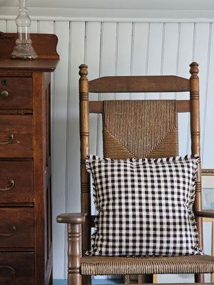 Enhance your living space with the Dark Brown Gingham Pillow, where timeless country charm meets refined design. Crafted from 100% cotton with a subtle off-white and dark brown gingham pattern, this pillow features elegant fringe edging and a discreet, easy-to-remove zipper. Its plush polyester insert offers both comfort and structure, making it a sophisticated accent that brings warmth and texture to any room. Spot clean only to preserve its quality. Measuring 18" x 18"