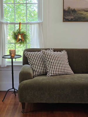 Enhance your living space with the Dark Brown Gingham Pillow, where timeless country charm meets refined design. Crafted from 100% cotton with a subtle off-white and dark brown gingham pattern, this pillow features elegant fringe edging and a discreet, easy-to-remove zipper. Its plush polyester insert offers both comfort and structure, making it a sophisticated accent that brings warmth and texture to any room. Spot clean only to preserve its quality. Measuring 18" x 18", it’s the perfect blend of classic s