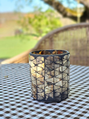 Add a bit of magical ambiance with our Mercury Glass Mosaic Candle Holder. Features aged mirrored glass that sparkles with silver, rose and golden hues. The mirrored glass also picks up the hues of the room decor, making this piece blend in effortlessly with its surroundings. The shimmering glow of candlelight through the cut pattern is dreamy. Holds one votive candle. 2.75" Diam x 3.25"H