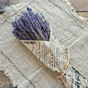 Our French Lavender Bouquet is a nod to the timeless elegance of the French countryside. This Super Blue Lavender is cultivated by generations of passionate French farmers. Each 80-gram bunch stands as a testament to tradition and quality. Wrapped in newsprint tissue paper that resonates with nostalgia, this lavender is a journey back in time. Hand-wrapped and graced with a natural raffia bow, it's more than just lavender; it's a piece of history. Each bundle is approximately 14" long. Made in France.