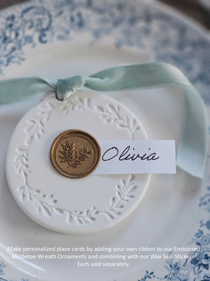 Decorative ornament with a wax seal sticker and ribbon on a patterned surface