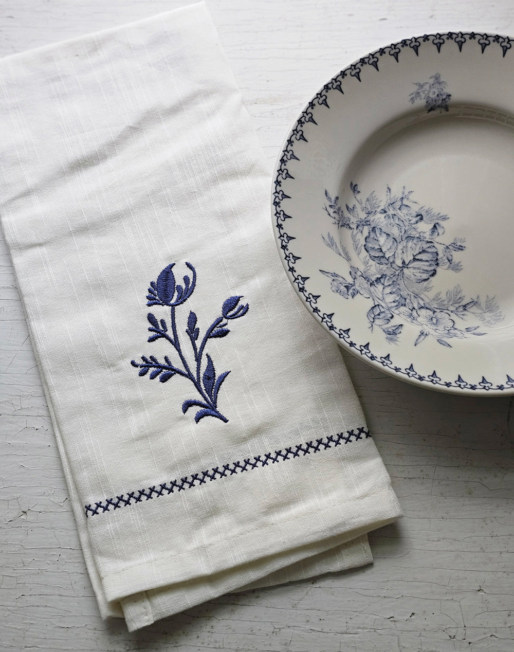 https://farmhousewares.com/cdn/shop/files/Embroidered-Dish-Towel-with-Delft-Blue-Sprig-with-Transferware-V_2048x.jpg?v=1701451939
