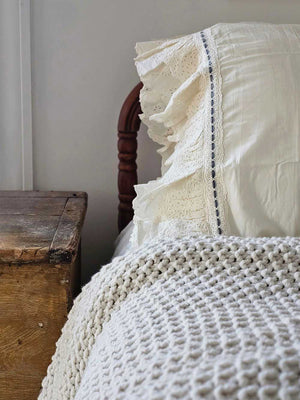 Our Eyelet Ruffles with Velvet Ribbon Pillowcase, Set of Two lends dreamy cottage style to any bedroom. These cream pillowcases feature a double layer of ruffle edges with exquisite floral eyelet detail with a grey blue velvet ribbon woven through a crochet border. The cream color is warm, falling on the yellow spectrum. This lace edge pillowcase will add texture and a charming vintage look to your room. Ribbon color may vary slightly.