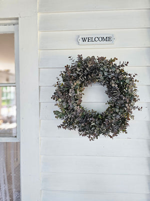 The soft, muted grey/green tones, with hints of muted purple and plum, lend an earthy charm to this Faded Purple Eucalyptus Wreath. The colors of the faux eucalyptus branches create a rich, moody, and rustic feel that looks beautiful in any season. The frame is made of bundled grapevine. 18"