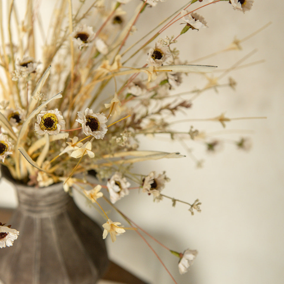 Farmhouse cottage style is made easy with our Faded Cream Wildflower and Grass Spray. This faux flower spray features a lush array of sweet daisy-like blossoms and wispy grasses. The stem is long, slender, and flexible and is easily shaped for a desired look. It can be displayed alone for a simple country look or arranged into a bouquet. It easily fits into baskets, buckets, and milk cans and more.