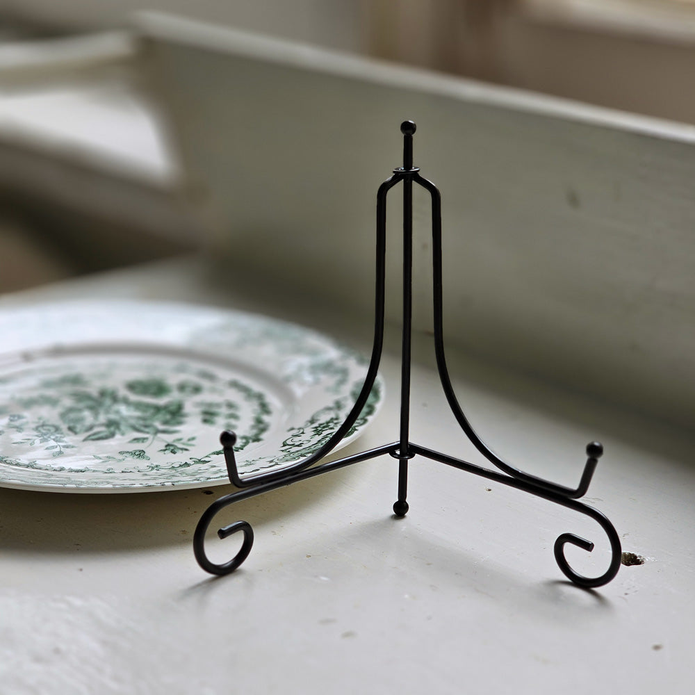 The Folding Plate Display Stand is a decorative plate holder made of smooth black iron material. The holder comes in an A-frame shape, able to fold together, for easy storage. Pair this holder with a decorative plate for a year-round display on any shelf, tabletop, or other flat surface. Holds dishes 6-8" in diameter.