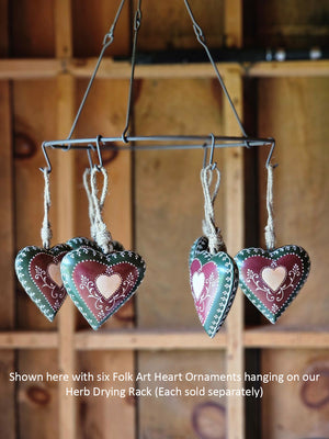This sweet Folk Art Heart Ornament adds cottage style all year long. Crafted from durable iron, each heart-shaped ornament comes in rich burgundy and deep green hues, accented with bright white details. A center light pink heart motif and heritage-style vine design gives this ornament a timeless, handcrafted feel, while the twine hanger adds a rustic finishing touch.  Each sold separately
