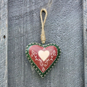 This sweet Folk Art Heart Ornament adds cottage style all year long. Crafted from durable iron, each heart-shaped ornament comes in rich burgundy and deep green hues, accented with bright white details. A center light pink heart motif and heritage-style vine design gives this ornament a timeless, handcrafted feel, while the twine hanger adds a rustic finishing touch. 