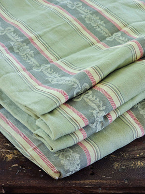Our French Fabric by the Yard features a vintage style Green Woven Jacquard. The intricate woven detail features darker green bands with woven flower and bow pattern accented with red stripes. Bring the elegance of French Country style to any project.

This is a high quality cotton fabric that can be used for upholstery, curtains, pillows, and more.

Made In France.